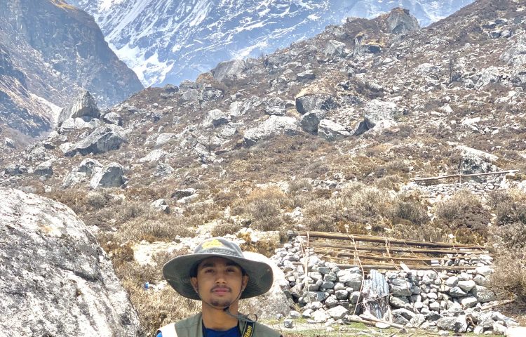 Samar Baniya standing in front of majestic Himalayas.